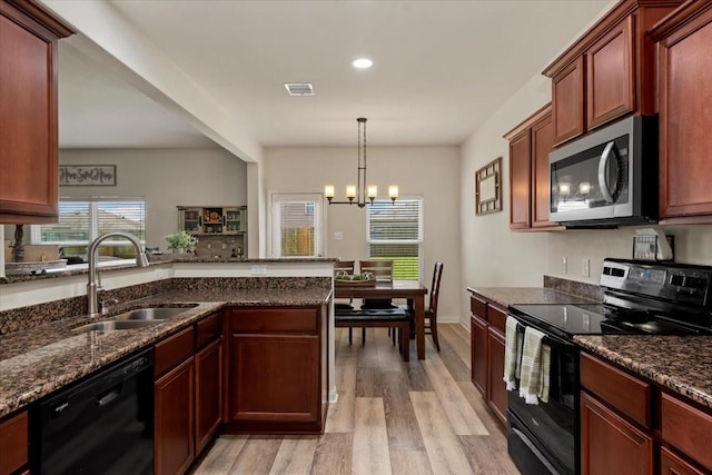 22435 Base Light Dr, Hockley, TX 77447 - kitchen featuring black appliances, light wood-type flooring, dark stone countertops, a chandelier, and recessed lighting