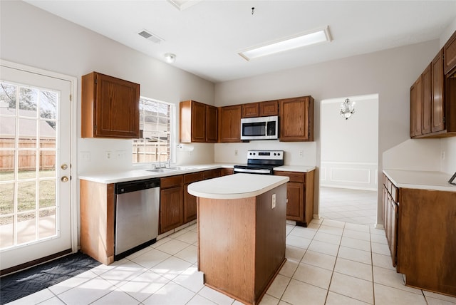 814 Hyacinth Pl, Missouri City, TX 77459 - kitchen with stainless steel appliances, a kitchen island, light countertops, a sink, and brown cabinetry