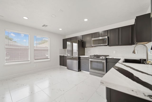 6519 Portlick Dr, Katy, TX 77449 - kitchen featuring appliances with stainless steel finishes, recessed lighting, backsplash, light marble finish floors, and light stone countertops