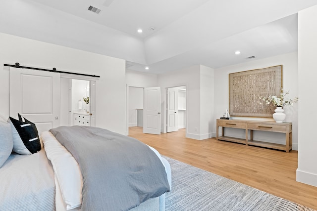 937 Louise St, Houston, TX 77009 - bedroom featuring light wood-type flooring, a barn door, recessed lighting, baseboards, and a spacious closet