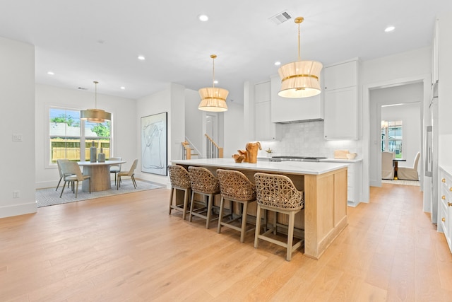 937 Louise St, Houston, TX 77009 - kitchen with light wood-style flooring, decorative backsplash, light countertops, white cabinets, and recessed lighting