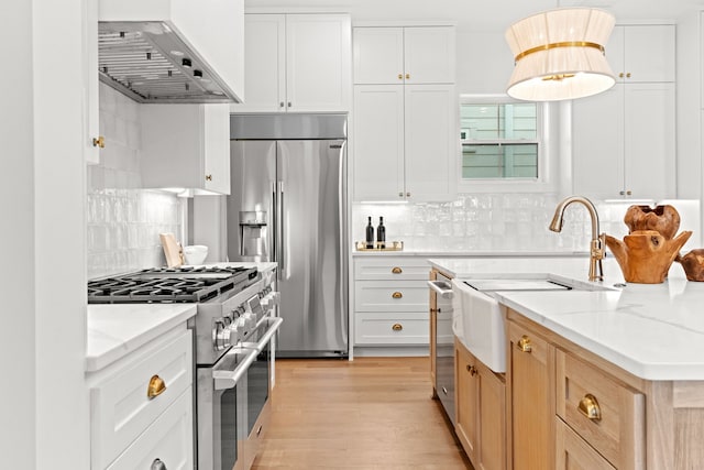 937 Louise St, Houston, TX 77009 - kitchen with wall chimney exhaust hood, appliances with stainless steel finishes, a sink, backsplash, and light stone countertops