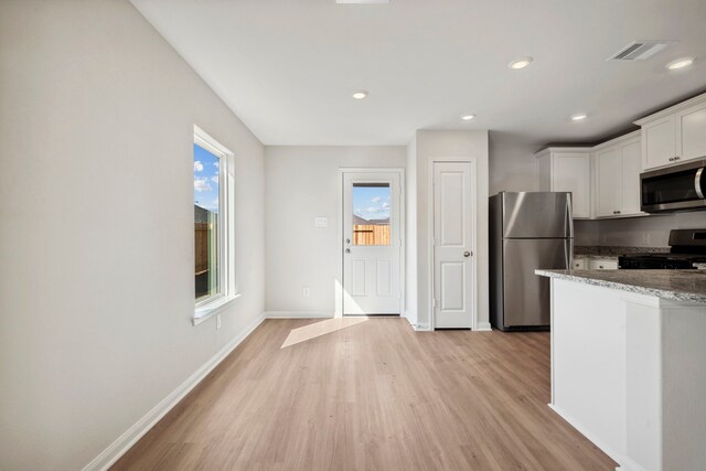 412 Tejas Trl, Waller, TX 77484 - kitchen with stainless steel appliances, light wood-type flooring, stone counters, white cabinets, and baseboards