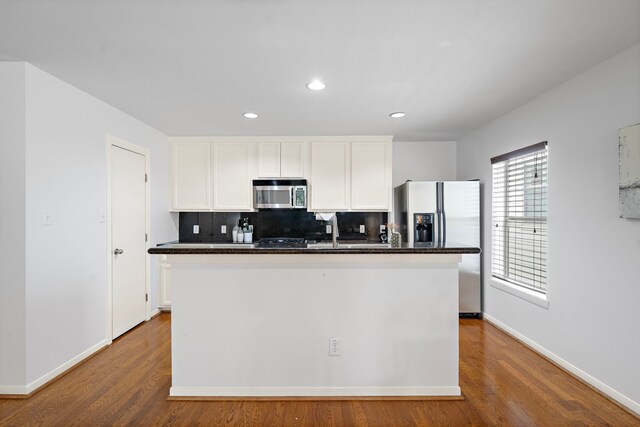 1918 Prospect St, Houston, TX 77004 - kitchen featuring stainless steel microwave, dark countertops, white cabinets, backsplash, and refrigerator with ice dispenser