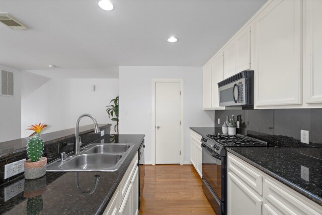 1918 Prospect St, Houston, TX 77004 - kitchen featuring black appliances, white cabinetry, dark wood-style floors, recessed lighting, and dark stone countertops