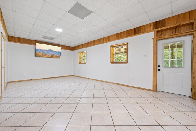 13236 Fm 1409 Unit A, Dayton, TX 77535 - empty room featuring a paneled ceiling, plenty of natural light, baseboards, wooden walls, and light tile patterned floors