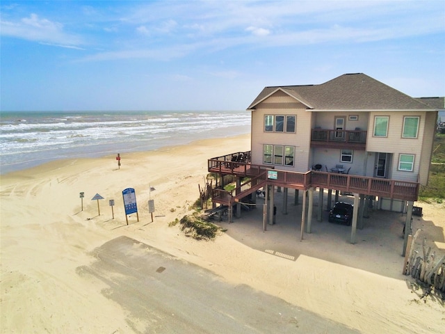 107 Yucca Ave, Surfside Beach, TX 77541 - back of property featuring a carport, view of water and beach, a balcony, roof with shingles, and stairs