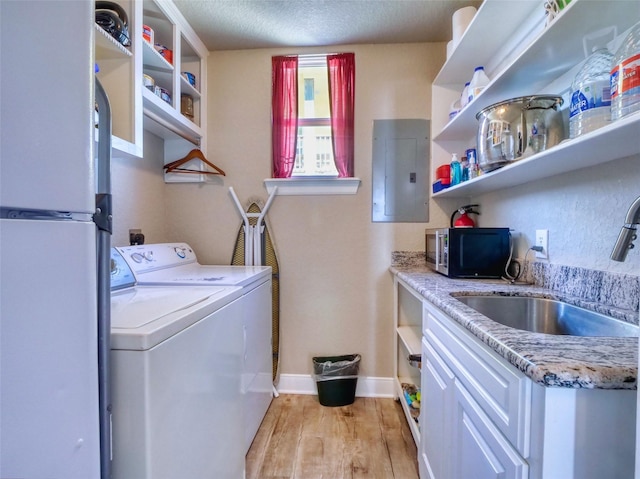 107 Yucca Ave, Surfside Beach, TX 77541 - laundry room with washer / clothes dryer, electric panel, light wood finished floors, baseboards, and a textured ceiling