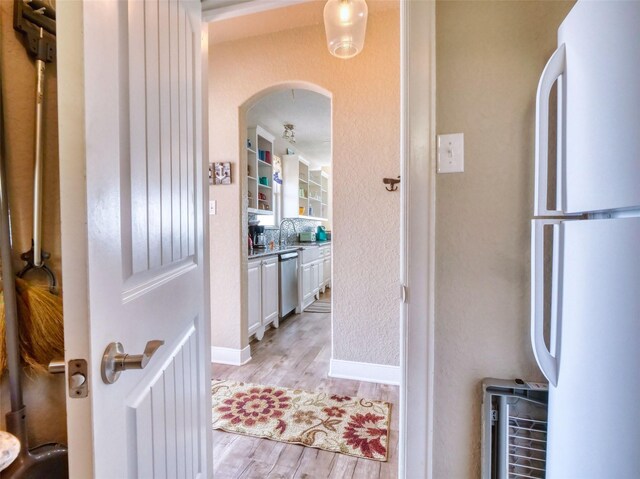 107 Yucca Ave, Surfside Beach, TX 77541 - hall with light wood-style floors, arched walkways, a sink, and baseboards