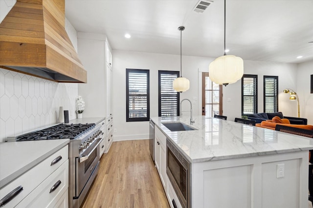 4731 Park Dr, Houston, TX 77023 - kitchen with appliances with stainless steel finishes, a sink, custom exhaust hood, decorative backsplash, and light wood finished floors