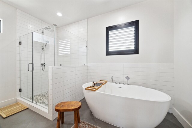 4731 Park Dr, Houston, TX 77023 - bathroom with tile walls, a shower stall, a soaking tub, tile patterned flooring, and wainscoting
