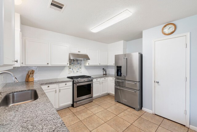 12007 Bach Orchard Trl, Houston, TX 77038 - kitchen with stainless steel appliances, under cabinet range hood, a sink, white cabinetry, and light tile patterned floors