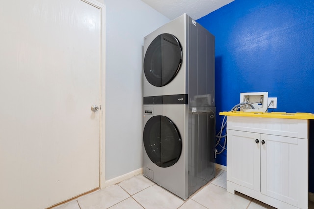 12007 Bach Orchard Trl, Houston, TX 77038 - laundry area with stacked washer / dryer, light tile patterned floors, cabinet space, and baseboards