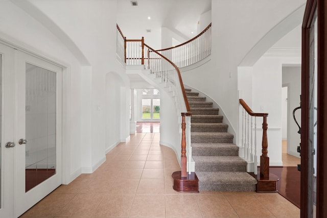 13202 Brushy Knoll Ln, Sugar Land, TX 77498 - foyer featuring arched walkways, light tile patterned flooring, stairs, a high ceiling, and baseboards