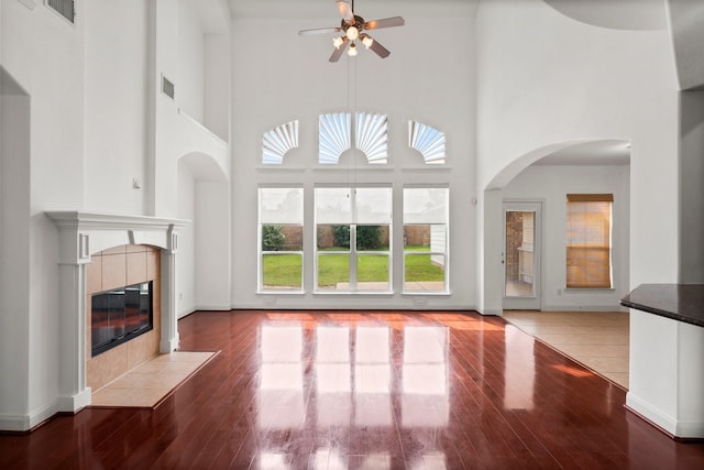 13202 Brushy Knoll Ln, Sugar Land, TX 77498 - unfurnished living room featuring ceiling fan, a fireplace, a towering ceiling, and wood-type flooring