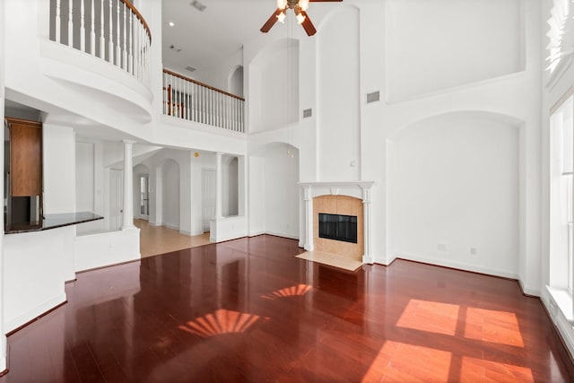 13202 Brushy Knoll Ln, Sugar Land, TX 77498 - unfurnished living room featuring a high ceiling, a ceiling fan, wood finished floors, a tile fireplace, and baseboards