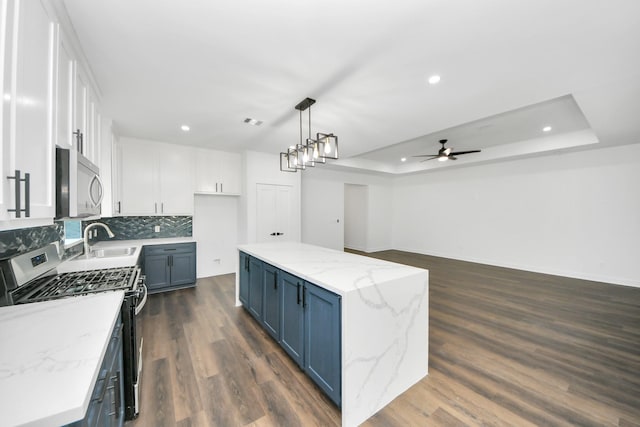 7440 Avenue E Ave E, Beasley, TX 77417 - kitchen featuring stainless steel appliances, a sink, a raised ceiling, recessed lighting, and blue cabinetry