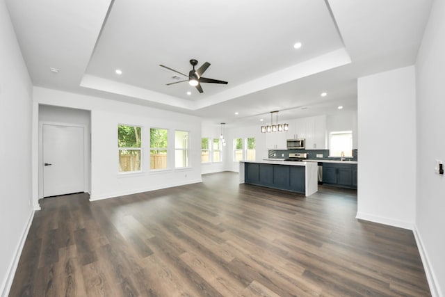 7440 Avenue E Ave E, Beasley, TX 77417 - unfurnished living room featuring a tray ceiling, a ceiling fan, baseboards, recessed lighting, and dark wood-style floors