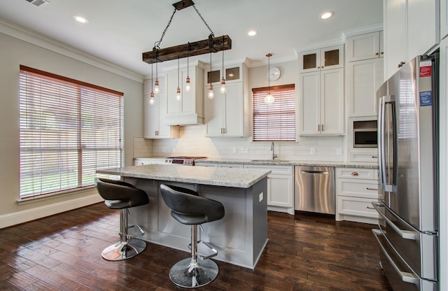 4303 Jonathan St, Bellaire, TX 77401 - kitchen featuring stainless steel appliances, ornamental molding, tasteful backsplash, a center island, and white cabinetry