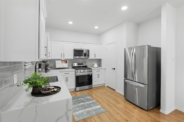 20419 Thunder Ridge Ln, Katy, TX 77449 - kitchen with appliances with stainless steel finishes, white cabinets, decorative backsplash, light wood-style floors, and recessed lighting