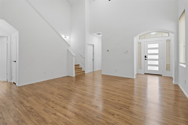 20419 Thunder Ridge Ln, Katy, TX 77449 - unfurnished living room featuring a high ceiling, stairs, light wood-type flooring, and baseboards