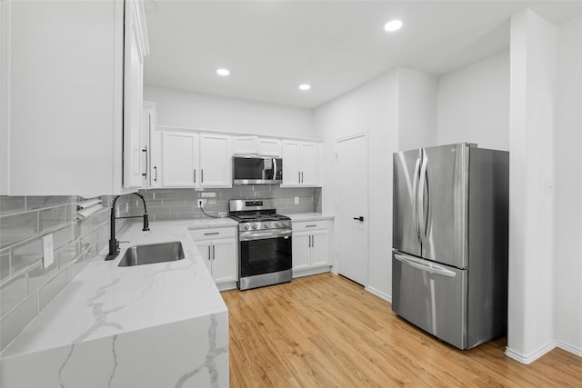 20419 Thunder Ridge Ln, Katy, TX 77449 - kitchen with stainless steel appliances, a sink, light wood-type flooring, white cabinets, and recessed lighting