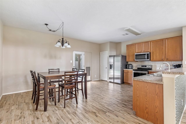 703 Windlass Way, Crosby, TX 77532 - kitchen with appliances with stainless steel finishes, a sink, light wood-style floors, backsplash, and a textured ceiling