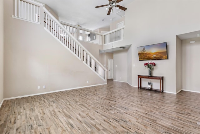 703 Windlass Way, Crosby, TX 77532 - unfurnished living room with a ceiling fan, stairway, wood finished floors, baseboards, and a high ceiling