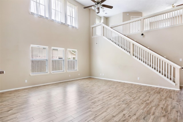 703 Windlass Way, Crosby, TX 77532 - unfurnished living room with ceiling fan, wood finished floors, healthy amount of natural light, and a towering ceiling