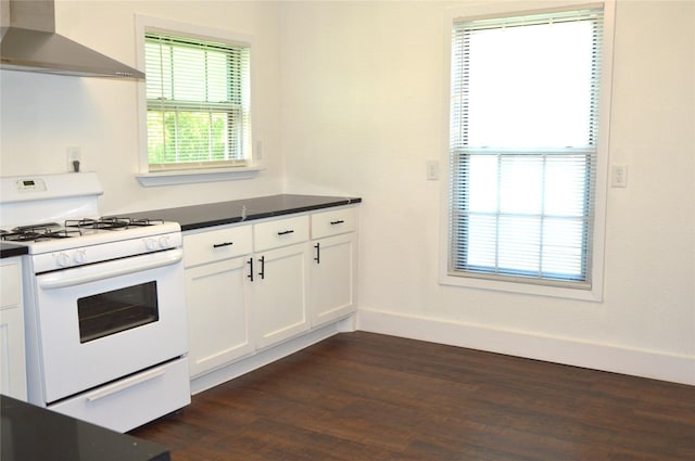 405 W Jack St, Baytown, TX 77520 - kitchen featuring white range with gas stovetop, wall chimney exhaust hood, dark countertops, dark wood finished floors, and baseboards