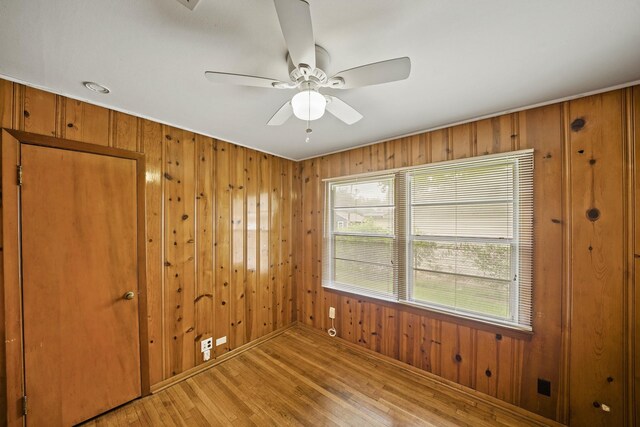 5814 Darnell St, Houston, TX 77074 - empty room featuring light wood-type flooring, wood walls, a ceiling fan, and baseboards