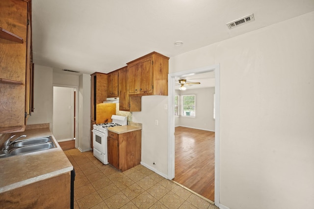 5814 Darnell St, Houston, TX 77074 - kitchen with white range with gas stovetop, a sink, under cabinet range hood, baseboards, and light countertops