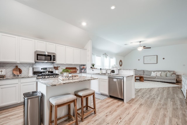 1004 Breech Dr, Crosby, TX 77532 - kitchen with appliances with stainless steel finishes, a sink, vaulted ceiling, white cabinets, and a peninsula