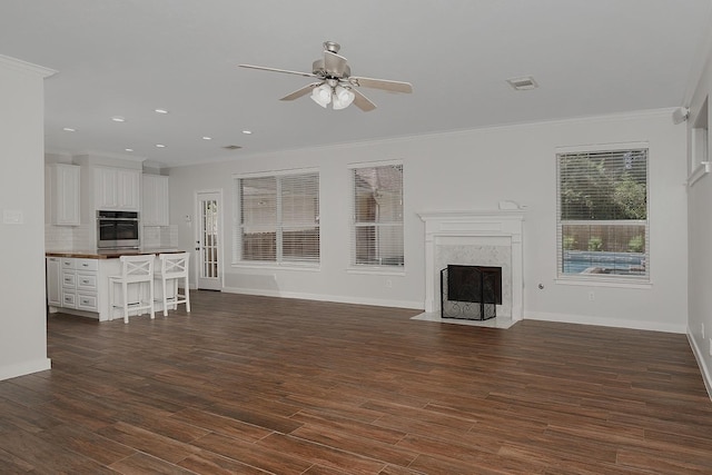 23 Shellbark, The Woodlands, TX 77382 - unfurnished living room featuring a premium fireplace, a ceiling fan, crown molding, baseboards, and dark wood-type flooring
