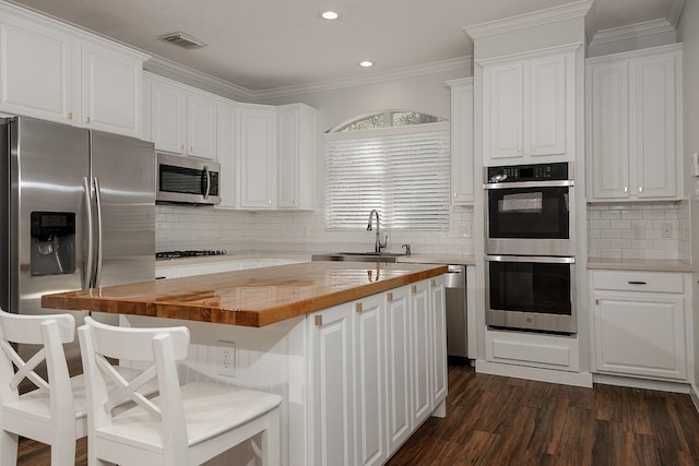 23 Shellbark, The Woodlands, TX 77382 - kitchen featuring appliances with stainless steel finishes, butcher block counters, white cabinets, a sink, and backsplash