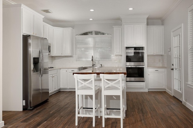 23 Shellbark, The Woodlands, TX 77382 - kitchen with stainless steel appliances, dark wood-style flooring, white cabinets, tasteful backsplash, and crown molding
