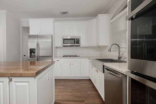 23 Shellbark, The Woodlands, TX 77382 - kitchen featuring appliances with stainless steel finishes, tasteful backsplash, dark wood-type flooring, white cabinets, and crown molding