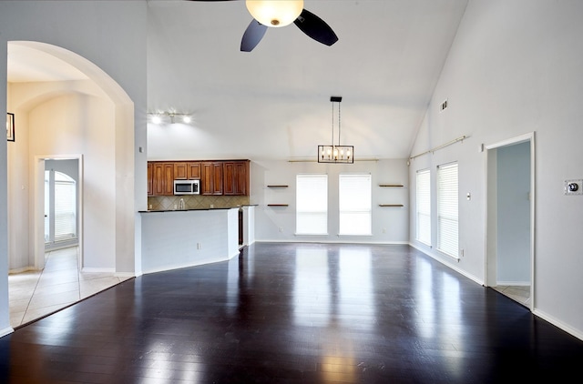 13012 Balsam Breeze Ln, Pearland, TX 77584 - unfurnished living room with high vaulted ceiling, ceiling fan, hardwood / wood-style floors, arched walkways, and a chandelier