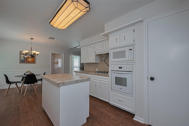 6526 Mert St, Katy, TX 77493 - kitchen featuring white appliances, under cabinet range hood, a chandelier, white cabinets, and a kitchen island