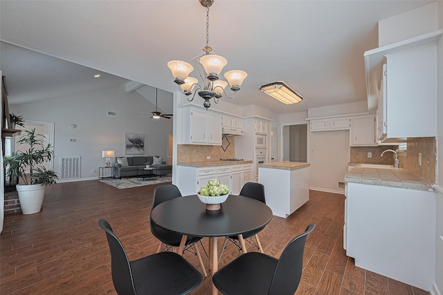 6526 Mert St, Katy, TX 77493 - dining space with ceiling fan, a chandelier, baseboards, lofted ceiling, and dark wood-style flooring
