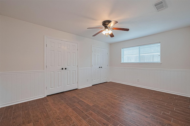 6526 Mert St, Katy, TX 77493 - unfurnished bedroom featuring multiple closets, dark wood-style floors, a wainscoted wall, and ceiling fan