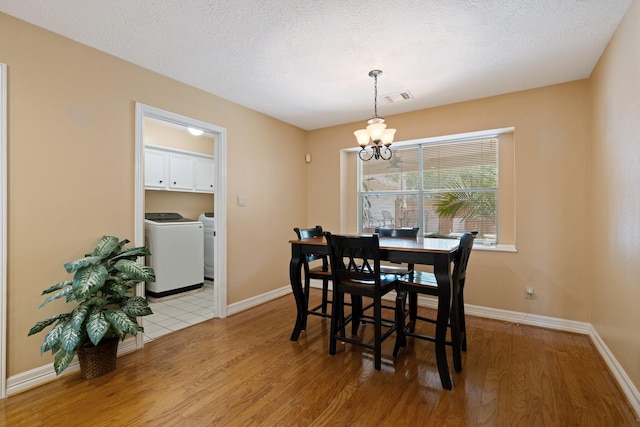 12910 Lake Mist Dr, Cypress, TX 77429 - dining area featuring light wood-type flooring, washing machine and clothes dryer, a chandelier, baseboards, and a textured ceiling