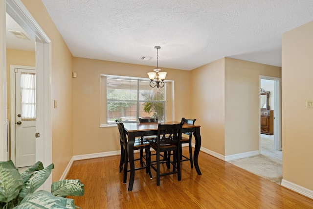 12910 Lake Mist Dr, Cypress, TX 77429 - dining area with light wood-type flooring, a chandelier, a textured ceiling, and baseboards