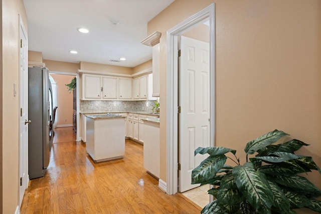 12910 Lake Mist Dr, Cypress, TX 77429 - kitchen with stainless steel fridge, tasteful backsplash, light wood finished floors, white cabinets, and a center island