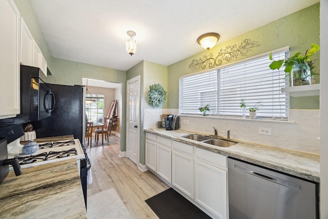 18614 Atasca Oaks Dr, Humble, TX 77346 - kitchen featuring stainless steel dishwasher, white range with gas cooktop, a sink, tasteful backsplash, and white cabinetry