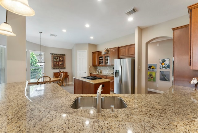 25514 Long Iron Ct, Spring, TX 77389 - kitchen with stainless steel refrigerator with ice dispenser, light stone counters, arched walkways, brown cabinets, and glass insert cabinets