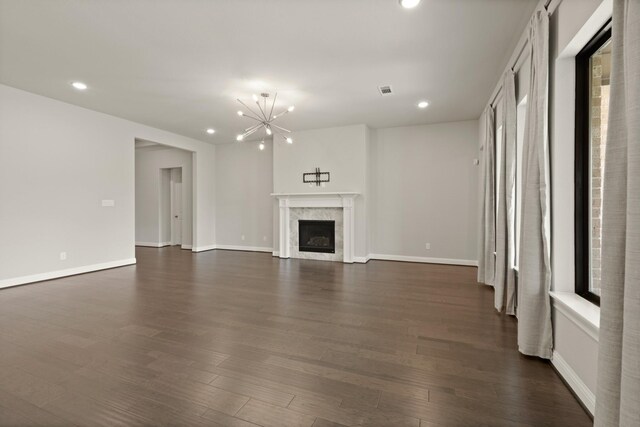 27423 Parker Spring Ct, Katy, TX 77494 - unfurnished living room with a chandelier, recessed lighting, dark wood-style flooring, baseboards, and a premium fireplace