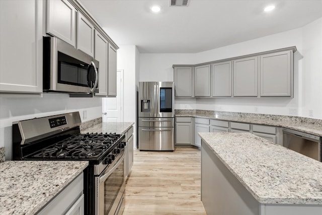21219 Mangrove Ln, Cypress, TX 77433 - kitchen featuring stainless steel appliances, gray cabinetry, light wood finished floors, light stone counters, and recessed lighting
