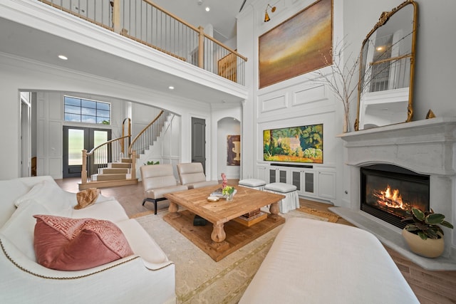 23323 Two Harbors Glen St, Katy, TX 77494 - living room with a towering ceiling, stairs, a glass covered fireplace, a decorative wall, and arched walkways