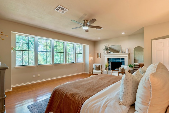 5343 Appleblossom Ln, Friendswood, TX 77546 - bedroom with wood finished floors, a tile fireplace, recessed lighting, a ceiling fan, and arched walkways